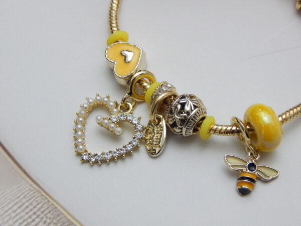 Yellow charm bracelet with bee pendant and pearl-crystal heart drop on gold chain