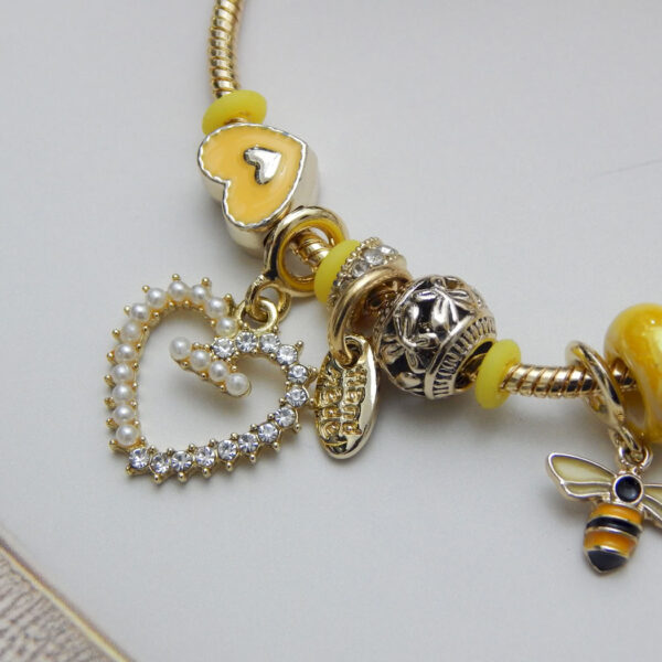 Yellow charm bracelet with bee pendant and pearl-crystal heart drop on gold chain