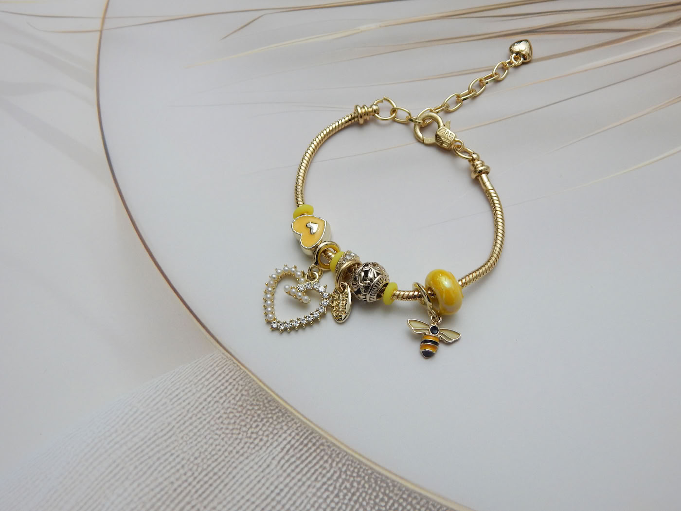 Yellow charm bracelet with bee pendant and pearl-crystal heart drop on gold chain