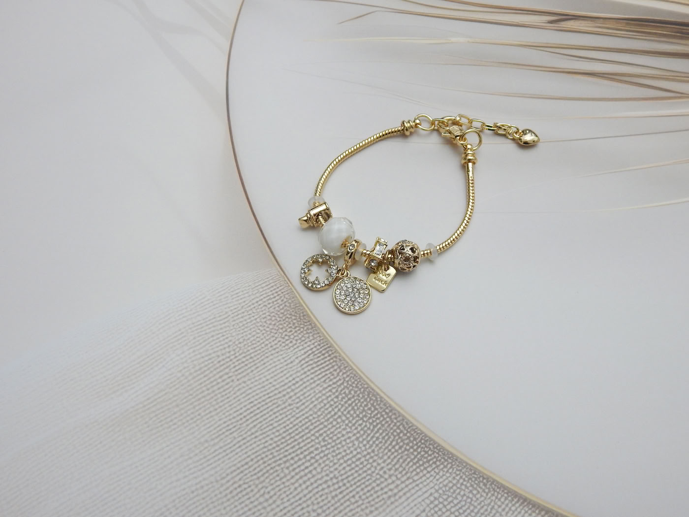 Elegant gold charm bracelet with good luck tag and crystal-studded white beads