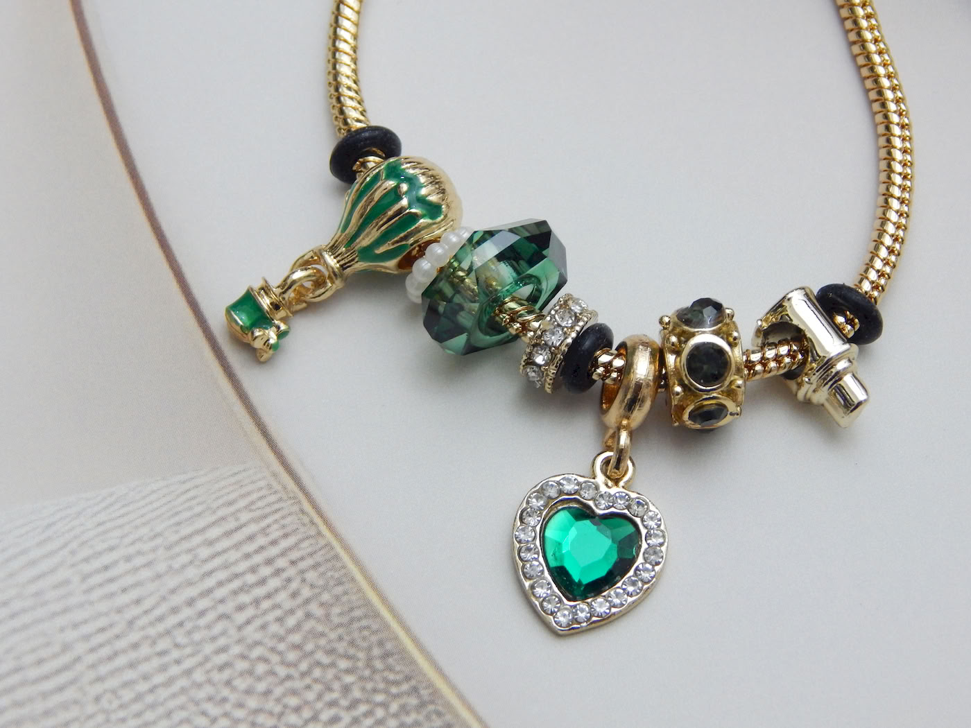 Bracelet featuring a green heart charm, glass balloon bead, Murano-style beads, and snake chain