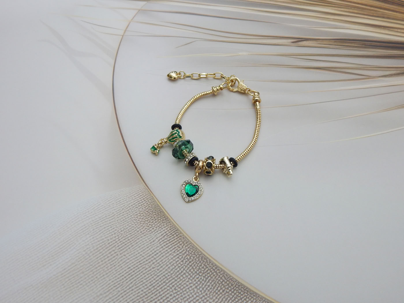 Bracelet featuring a green heart charm, glass balloon bead, Murano-style beads, and snake chain