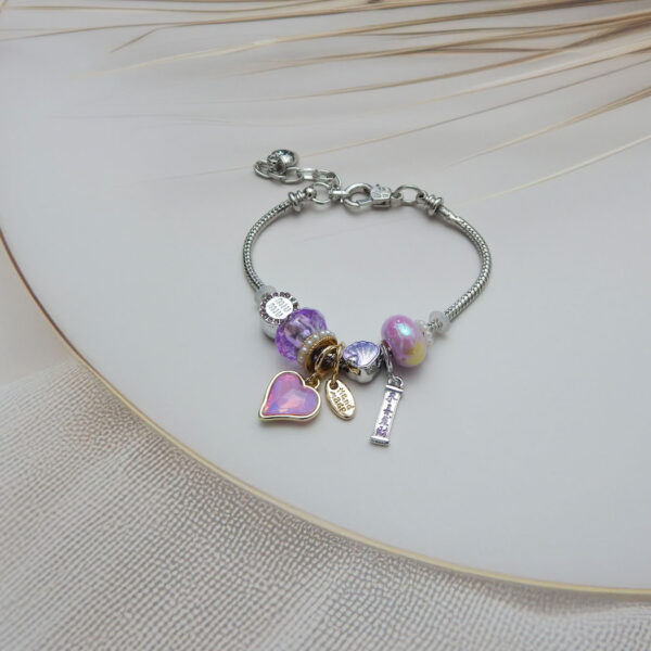 Pink Lavender Charm Bracelet with faceted heart, shell, and “Handmade” tag on silver-gold tone base