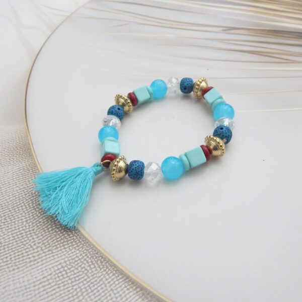 Boho-style bracelet with aqua and blue beads, red accents, and a turquoise tassel