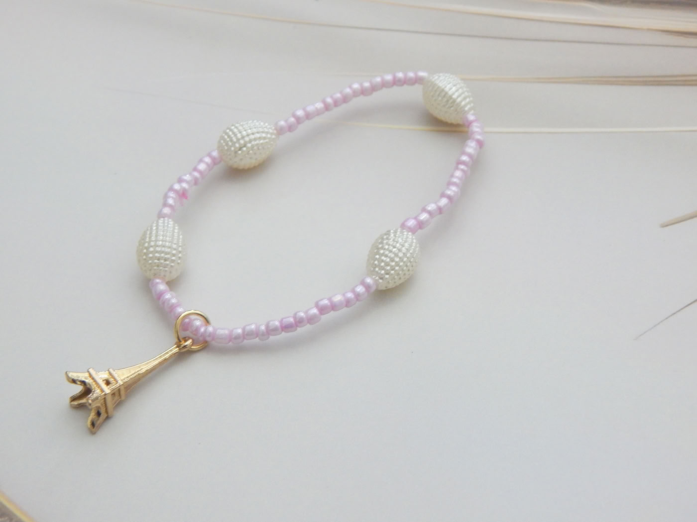 Light pink seed bead bracelet with pearl-look oval beads and Eiffel Tower charm