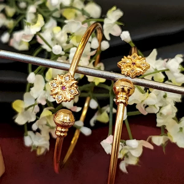 Minimalist golden kada with floral charm and ruby-accented center stone
