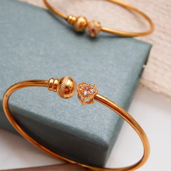 Gold-plated kada with heart-shaped stone charm and sparkling accents