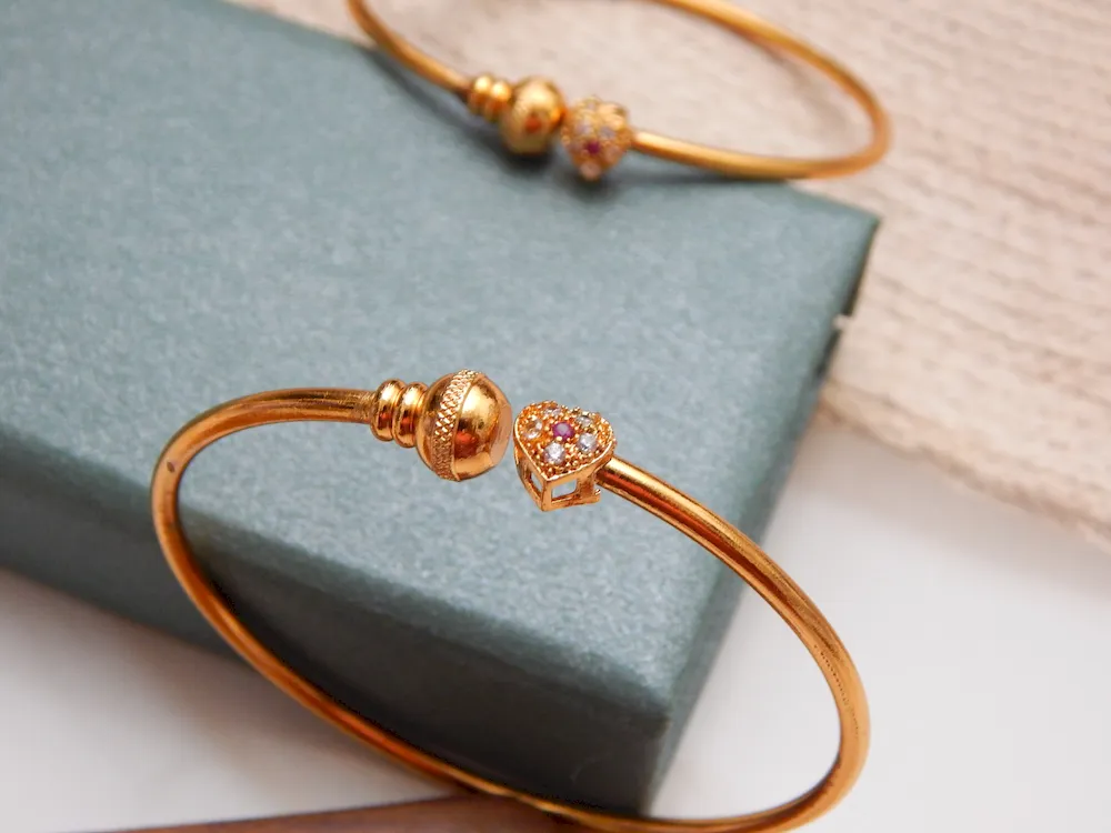 Gold-plated kada with heart-shaped stone charm and sparkling accents