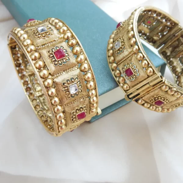 Broad antique gold kada with heritage motifs and red-white stones for festive and bridal wear