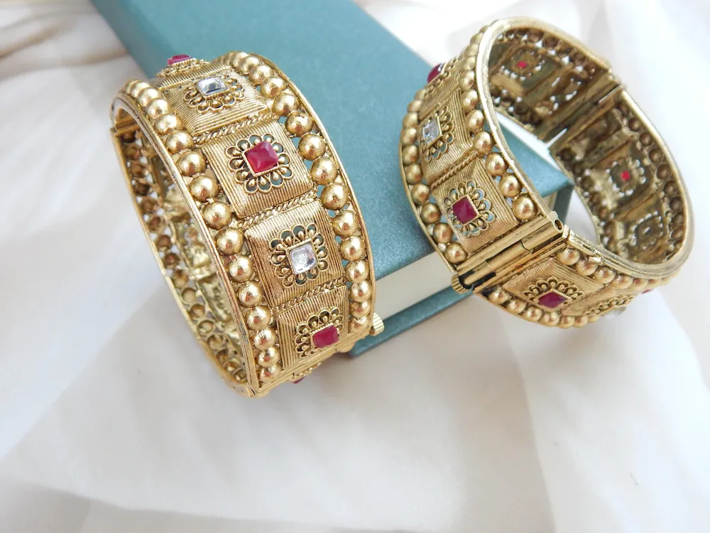 Broad antique gold kada with heritage motifs and red-white stones for festive and bridal wear