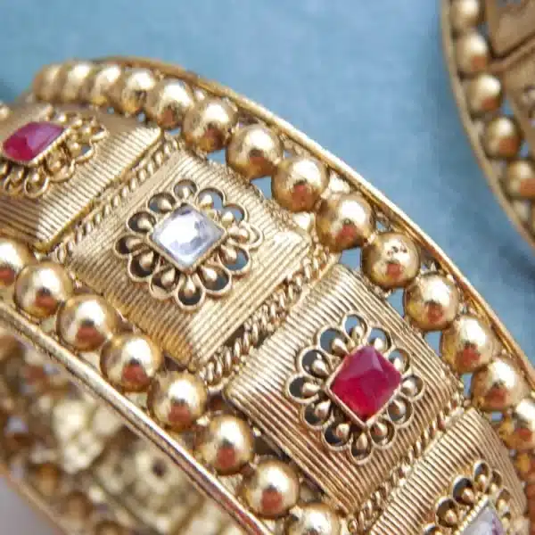 Broad antique gold kada with heritage motifs and red-white stones for festive and bridal wear