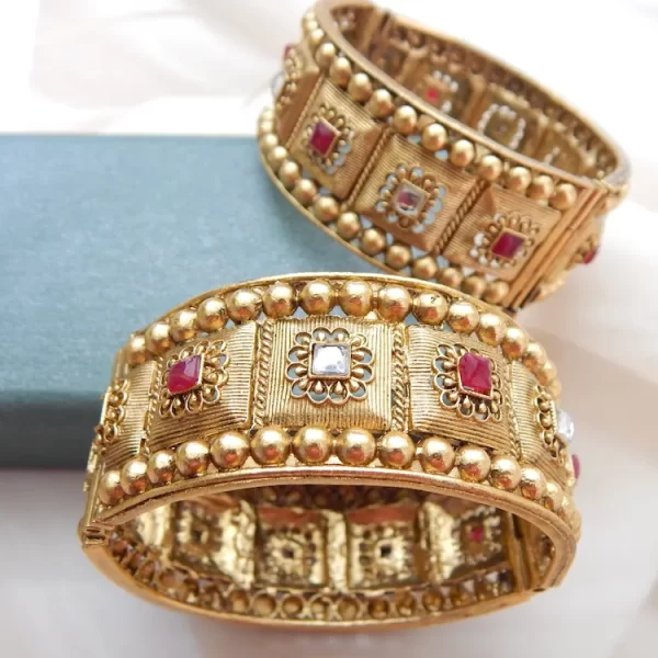 Broad antique gold kada with heritage motifs and red-white stones for festive and bridal wear
