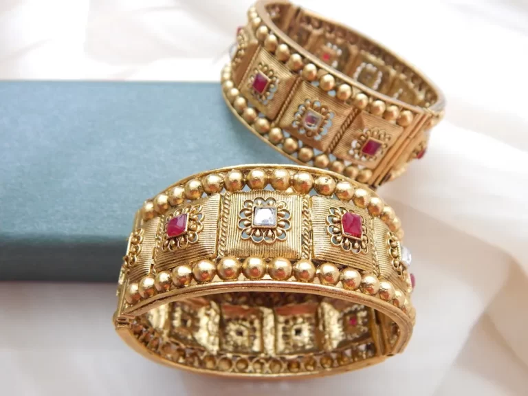 Broad antique gold kada with heritage motifs and red-white stones for festive and bridal wear