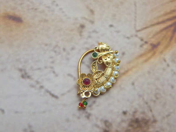 Traditional Maharashtrian floral pearl nath with red and green stones on a textured background