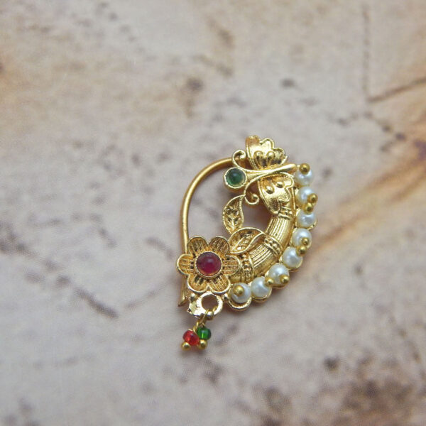 Traditional Maharashtrian floral pearl nath with red and green stones on a textured background
