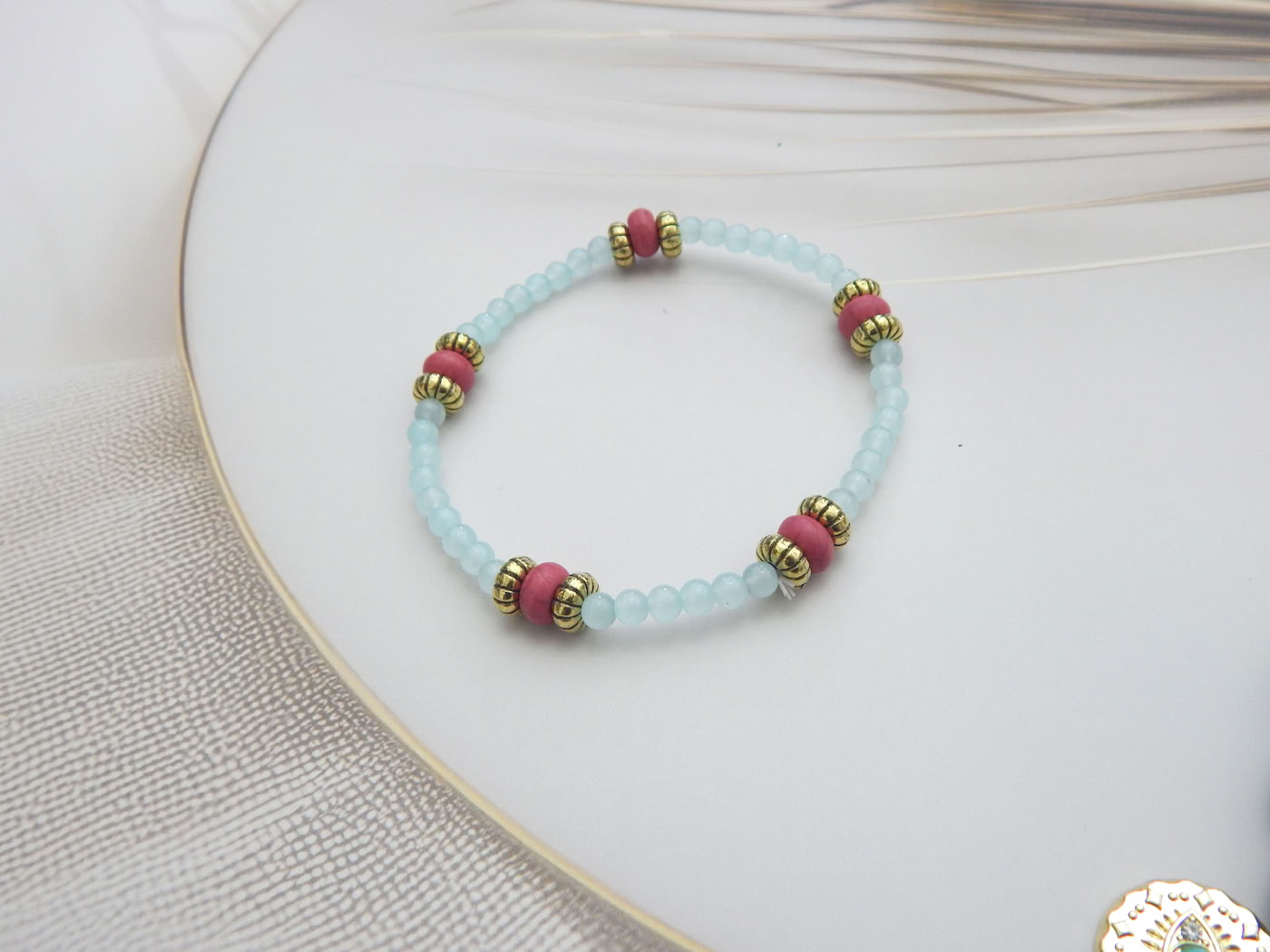 Light blue beaded bracelet with coral-toned and gold accent spacers