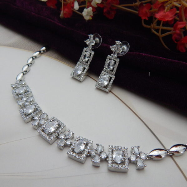 A stylish geometric necklace and earring set with alternating oval and square designs in a modern, silver-toned finish.