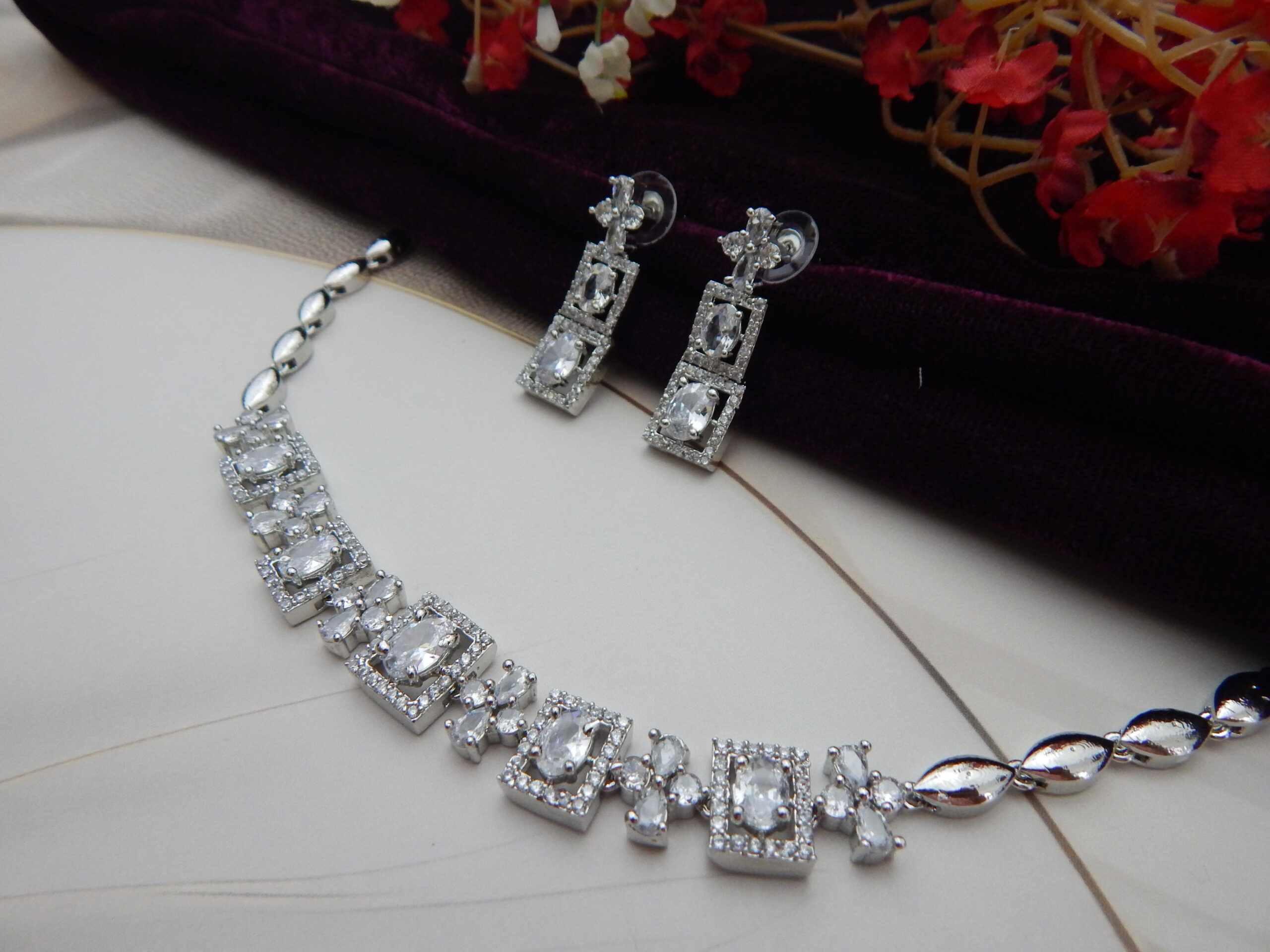 A stylish geometric necklace and earring set with alternating oval and square designs in a modern, silver-toned finish.