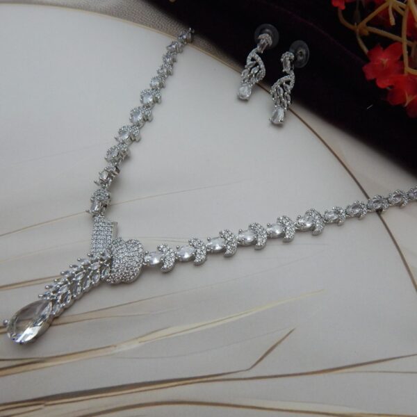 A graceful Y-shaped designer necklace with a teardrop pendant and matching drop earrings in a silver tone.