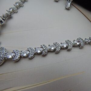 A graceful Y-shaped designer necklace with a teardrop pendant and matching drop earrings in a silver tone.