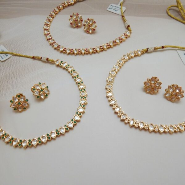 A set of three Kundan Polki choker necklaces and matching stud earrings, featuring a Kairi (paisley) design with variations in clear, green, and ruby stones.