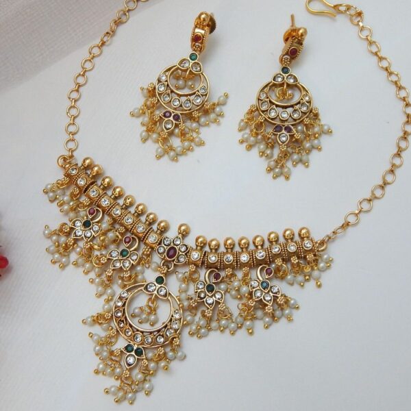 An antique matte gold choker necklace and earring set with a traditional design, featuring dangling pearls and red, green, and clear stones.