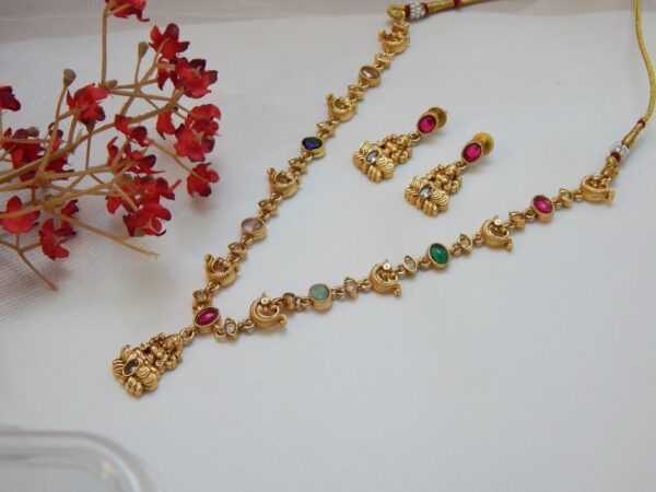 A short traditional temple jewelry necklace and earring set with a matte gold finish, featuring multiple colored gemstones and small circular motifs.