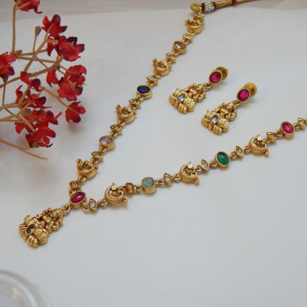 A short traditional temple jewelry necklace and earring set with a matte gold finish, featuring multiple colored gemstones and small circular motifs.