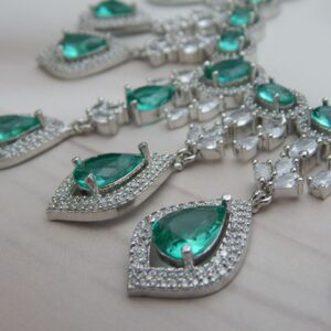 Close-up of the Noorjahan statement necklace and earring set featuring a cascade of green pendants and a silver finish.
