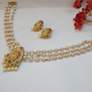 A traditional three-strand pearl necklace with a matte gold Laxmi pendant and matching stud earrings.