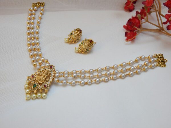 A traditional three-strand pearl necklace with a matte gold Laxmi pendant and matching stud earrings.
