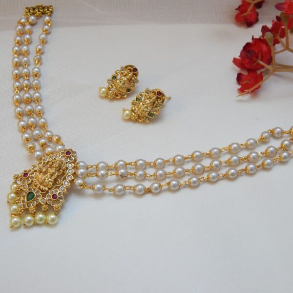 A traditional three-strand pearl necklace with a matte gold Laxmi pendant and matching stud earrings.