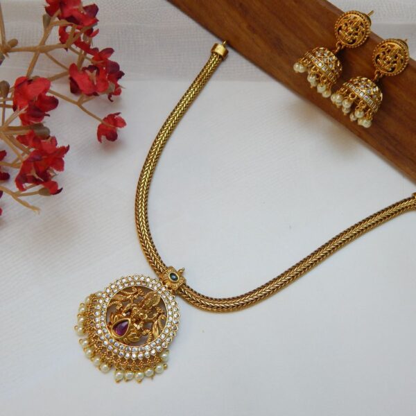 A traditional temple jewelry short necklace with a snake chain and a round goddess pendant with cubic zirconia stones and a single pearl drop.