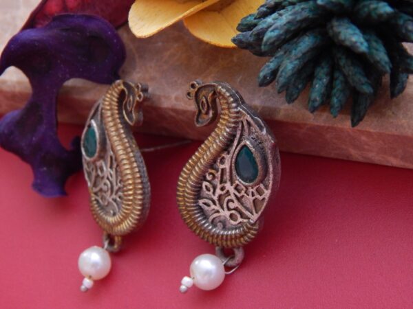 A pair of antique dual-tone stud earrings in a paisley shape with a green stone and a pearl drop.