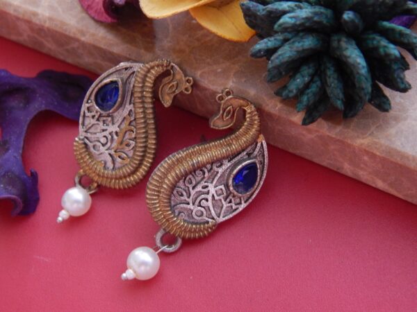 A pair of antique dual-tone stud earrings in a paisley shape with a royal blue stone and a pearl drop.