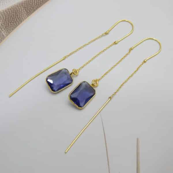 Long gold threader earrings with a hanging blue/violet rectangle cut stone.