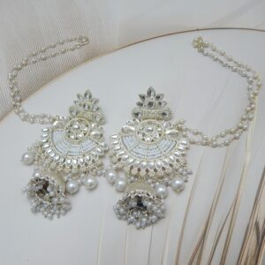A pair of silver-toned bridal jhumka earrings with an intricate design, adorned with pearls and an attached pearl chain.
