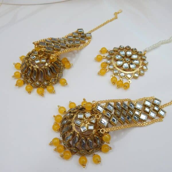 A Kundan maang tikka and matching earrings set with large fan-shaped pendants and yellow beaded drops.
