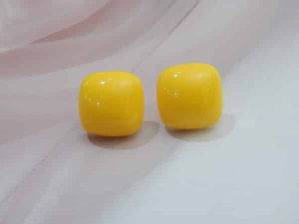 A pair of minimalist, glossy square-shaped stud earrings in a solid color