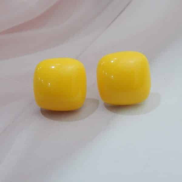 A pair of minimalist, glossy square-shaped stud earrings in a solid color