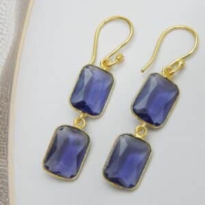 Gold-tone dangle earrings with two rectangular, faceted violet colored stones stacked vertically.