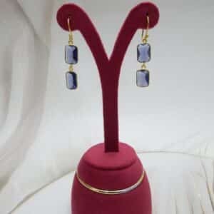Gold-tone dangle earrings with two rectangular, faceted violet colored stones stacked vertically.