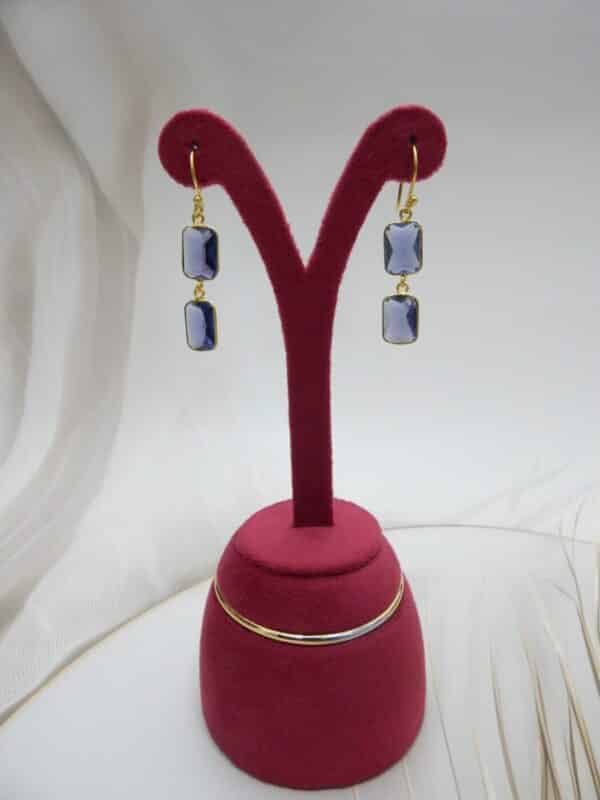 Gold-tone dangle earrings with two rectangular, faceted violet colored stones stacked vertically.