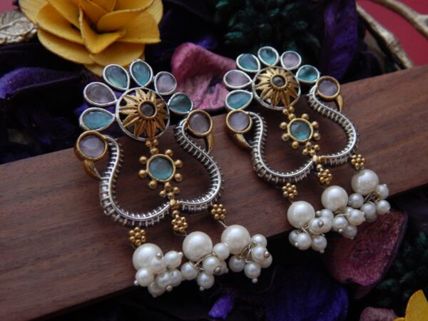 A pair of dual-tone oxidized silver and gold earrings with pinkish-grey Kundan-style stones and large pearl cluster dangles.