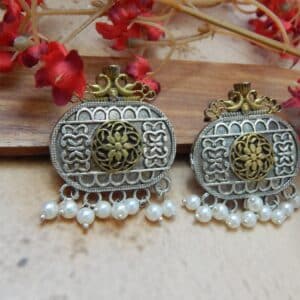 A pair of dual-tone oxidized silver and antique gold oval earrings with filigree work and white pearl dangles.