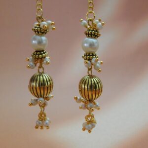 A pair of long, gold-toned dangler earrings with pearl beads and a ribbed oval bead, designed in a traditional style.
