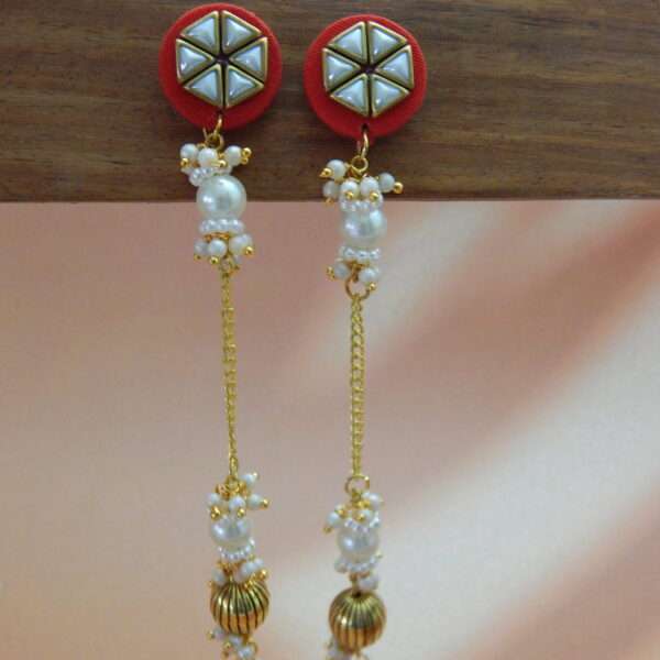 A pair of long, traditional red and gold-toned earrings with a geometric stud, hanging pearl drops, and a ribbed gold bead.