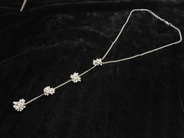 Delicate silver tone Y-shaped lariat necklace with floral bead clusters descending along the drop.