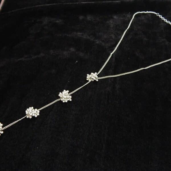Delicate silver tone Y-shaped lariat necklace with floral bead clusters descending along the drop.
