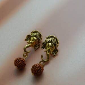 A pair of antique gold-toned earrings featuring an intricate Ganesha stud with a single rudraksha bead hanging below.